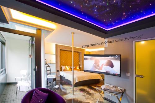 a bedroom with a bed and a flat screen tv at PLAZA INN stays design Dortmund in Dortmund