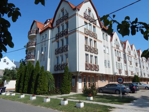 a large white building with balconies on a street at Oli Apartman in Hajdúszoboszló