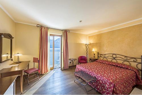 a bedroom with a bed and a desk and a window at La Darsena Boutique Hotel & Restaurant in Tremezzo