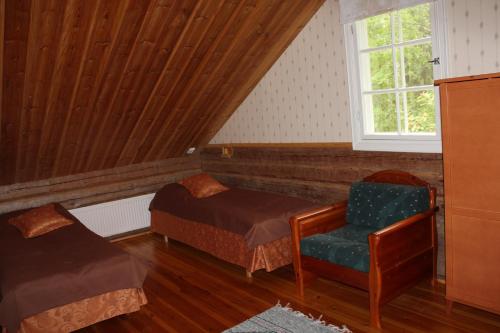 a bedroom with a bed and a chair and a window at Nukula Guestrooms in Oravasaari