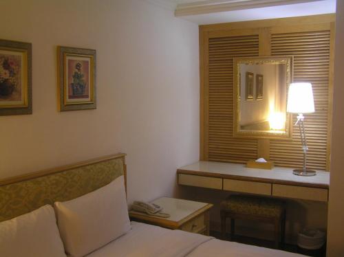 a bedroom with a bed and a desk and a lamp at 高第商旅 Gaudi Hotel in Kaohsiung