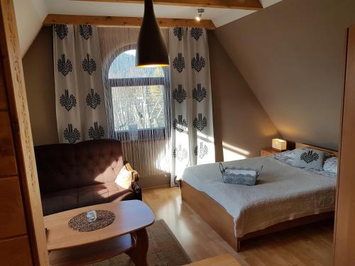 a bedroom with a bed and a couch and a window at Pokoje Gościnne Trebunia in Zakopane