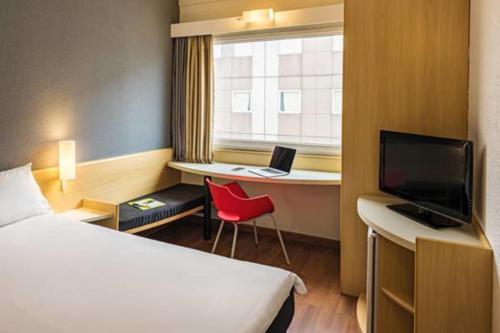 a hotel room with a bed and a desk with a laptop at ibis Tambore in Barueri