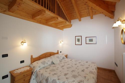 a bedroom with a bed and a wooden ceiling at Casa Rubino Lake & Dolomites in Molveno
