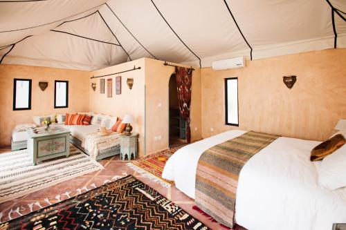 a bedroom with a bed and a couch in a tent at Villa Dinari in Douar Caïd Layadi