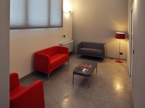 a waiting room with a red chair and a couch at BB Hotels Aparthotel Isola in Milan