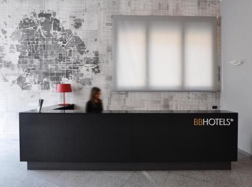 a woman sitting at a reception desk in an office at BB Hotels Aparthotel Isola in Milan