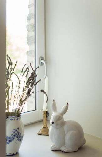 a white rabbit sitting on a table next to a vase at Le Logis de Tréonvel in Locmélar