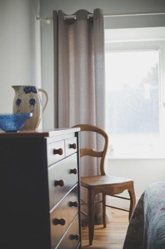 a bedroom with a dresser and a chair next to a window at Le Logis de Tréonvel in Locmélar