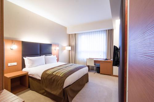 a hotel room with a bed and a desk at Ramada by Wyndham Oradea in Oradea
