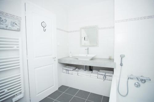 a white bathroom with a sink and a shower at Le Logis de Tréonvel in Locmélar