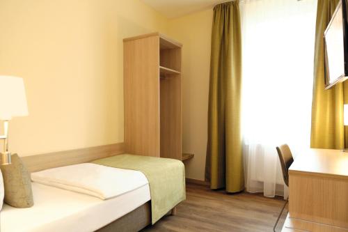 a small bedroom with a bed and a window at Hotel & Gasthaus DAS RÖHRL Straubing in Straubing