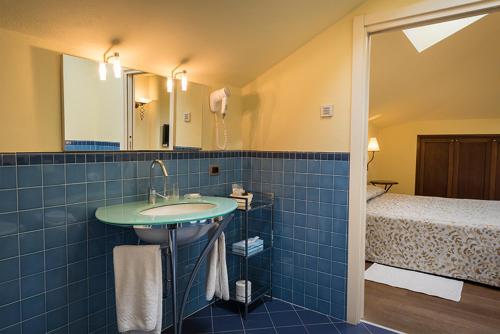 a blue tiled bathroom with a sink and a bed at La Darsena Boutique Hotel & Restaurant in Tremezzo