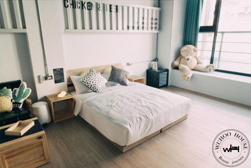 a bedroom with a bed with a teddy bear in it at Wuhoo House in Kaohsiung