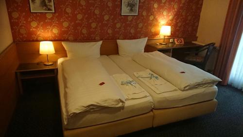 Ce lit se trouve dans une chambre d'hôtel dotée de 2 tables et de 2 lampes. dans l'établissement Haus Hilckmann, à Hörstel