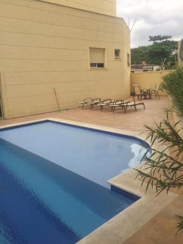 a swimming pool in front of a building with benches at Anitta 2 in Sao Paulo