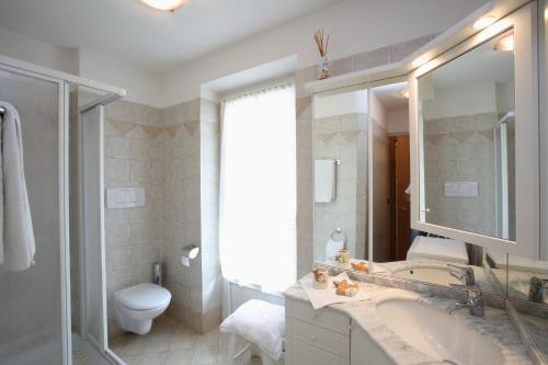 a bathroom with a sink and a toilet and a mirror at Casa Rubino Lake & Dolomites in Molveno