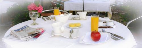 a white table with a plate with a fruit on it at Logis Hôtel et Restaurant du Dauphin in Sées