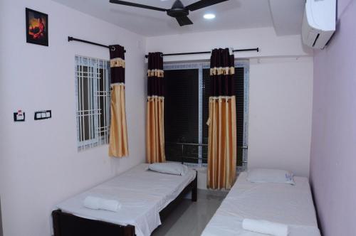 Zimmer mit 2 Betten und einem Fenster mit Vorhängen in der Unterkunft SGS Residency in Tirupati