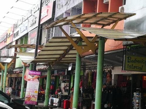 a store with green columns and a wooden canopy at Homestay Pulau Langkawi in Pantai Cenang