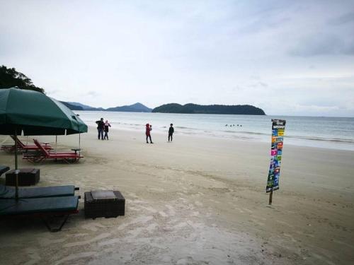 a group of people walking on the beach at Homestay Pulau Langkawi in Pantai Cenang
