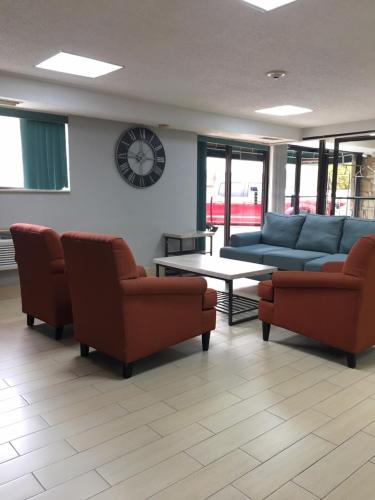 a waiting room with couches and a table and a clock at Floral Park Motor Lodge in Floral Park