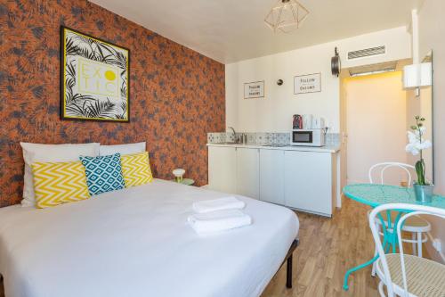 Cette petite chambre comprend un lit blanc et une cuisine. dans l'établissement WS Champs Elysées - Ponthieu, à Paris
