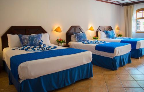 drie bedden in een kamer met blauw en wit bij El Tucano Resort & Thermal Spa in Quesada