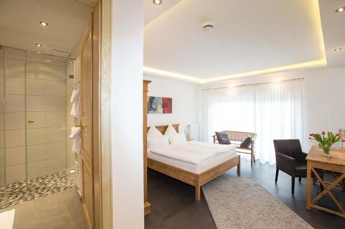 a bedroom with a bed and a table and a bathroom at Hotel Restaurant Daute in Iserlohn
