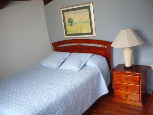 Un dormitorio con una cama y una lámpara en un tocador en Hostal Tutamanda 2, en Quito