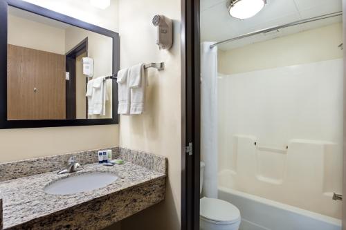 a bathroom with a sink and a toilet and a mirror at AmericInn by Wyndham Tomah in Tomah