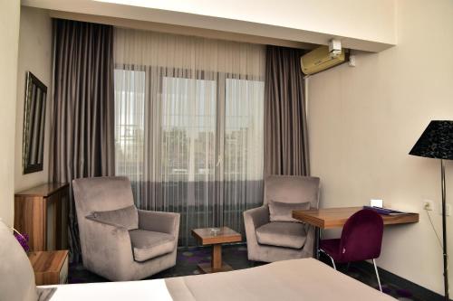a hotel room with two chairs and a table and a bed at Hande Hotel in Mustafakemalpaşa