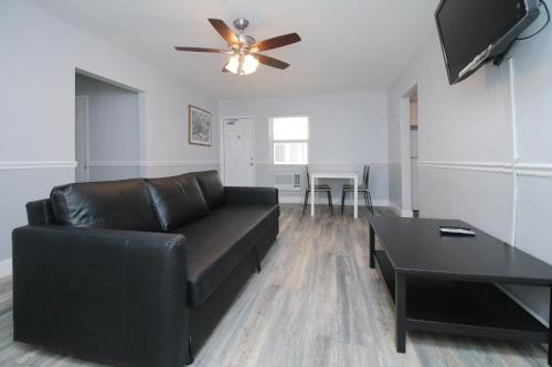 a living room with a black couch and a ceiling fan at The Dolphin Hollywood in Hollywood