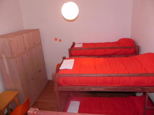 two beds in a small room with red sheets at Student’s Hostel in Montevideo