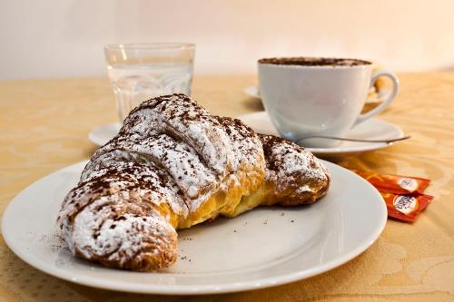 two pastries on a plate next to a cup of coffee at Blu Mediterraneo B&B in Messina