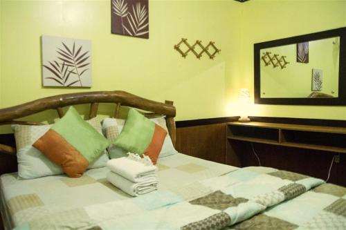 a bedroom with a bed with pillows and a mirror at Natura Vista in Panglao