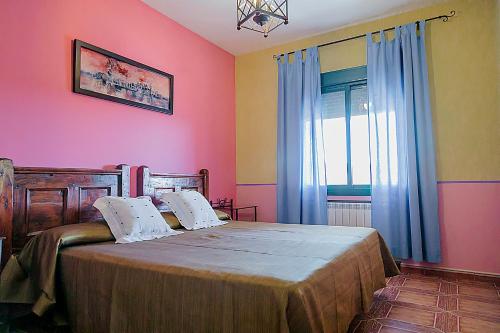 a bedroom with a bed with pink walls and a window at Apartamentos Los Panchos in Ruidera