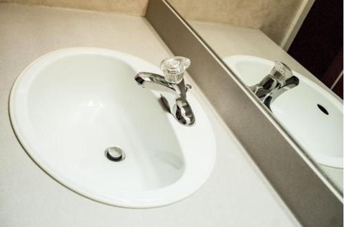 a white sink in a bathroom next to a mirror at Assiniboine Gordon Inn on the Park in Winnipeg
