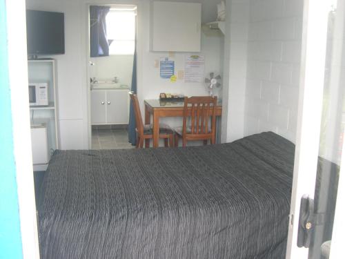 a room with a bed and a table and a kitchen at Strand Motel in Tauranga