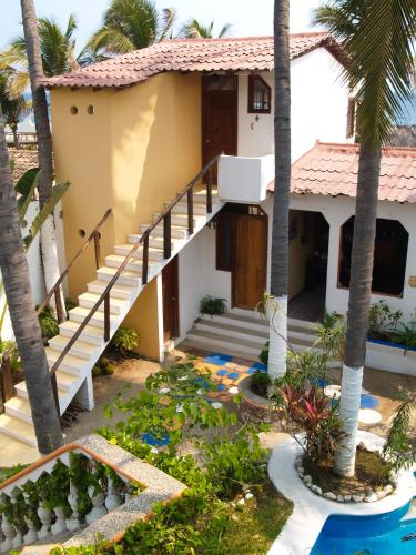 a house with palm trees in front of it at Hotel Gilda in Coyuca