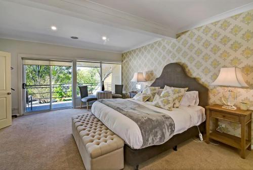 a large bedroom with a large bed and a chair at Bundanoon Lodge in Bundanoon