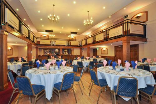 un salón de banquetes con mesas blancas y sillas azules en Dalton Inn Hotel en Claremorris