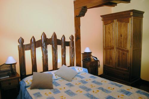 a bedroom with a wooden bed with pillows on it at Posada El Pescador in Oreña