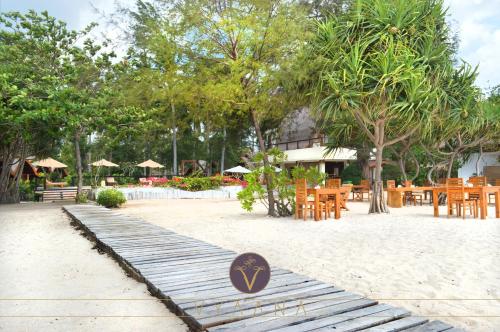 a wooden walkway on the beach with tables and chairs at Vyaana Resort Gili Air in Gili Air