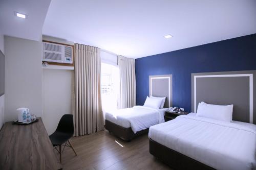 a hotel room with two beds and a window at S Hotel & Residences in Cebu City