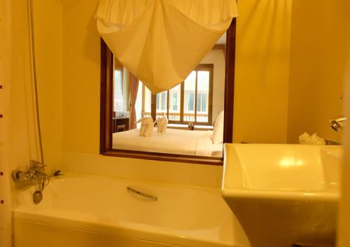 a bathroom with a mirror and a tub and a sink at Vieng Mantra Hotel in Chiang Mai