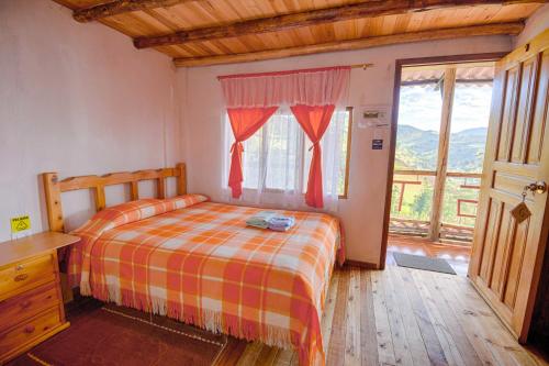 a bedroom with a bed and a large window at Hostal Taita Cristobal in Isinliví