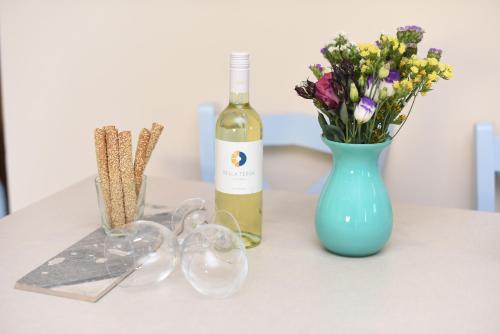 a bottle of wine and a vase of flowers on a table at Mon Emvasia Margarites Villas in Margarítai