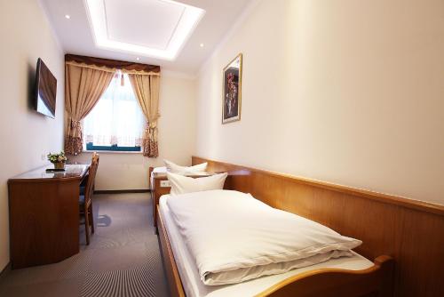 Schlafzimmer mit einem Bett, einem Schreibtisch und einem Fenster in der Unterkunft Hotel Europäischer Hof in Elsterwerda