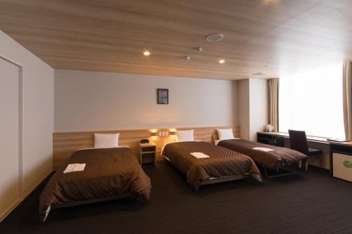 a hotel room with two beds and a window at Izumisano Center Hotel Kansai International Airport in Izumi-Sano